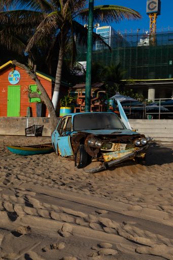 A vertical shot of an old broken car on the beach shore in Nha Trang