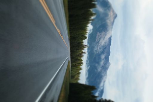 A smooth highway passing through a scenic forest; picturesque mountains in fog in the background