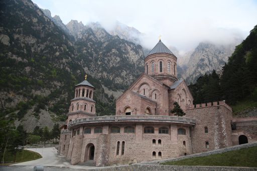 A beautiful shot of a Christian church with the trees and mountains in the background in Georgia