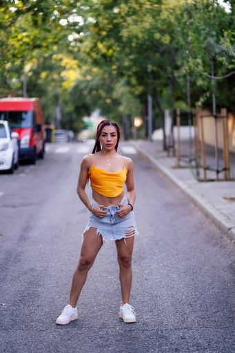 A vertical shot of a Hispanic woman with braids posing outdoors