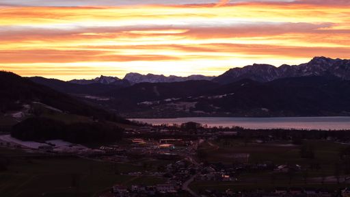 Fiery sky over the lake with a majestic mountain in the background. A stunning display of vibrant colors and natural beauty.