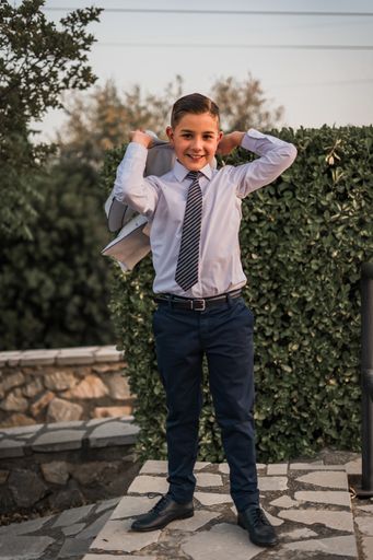 A vertical shot of an adorable male child in a formal suit outfit posing