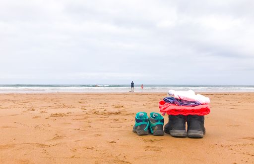 Two pairs of hiking boots, one for an adult and the other for a child, on a beach in Spain
