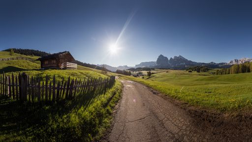 The mesmerizing view of the road in a village surrounded by green fields and mountains