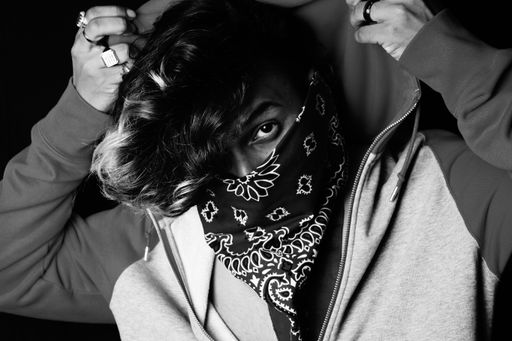 A grayscale shot of an Asian person wearing a hoodie and bandana