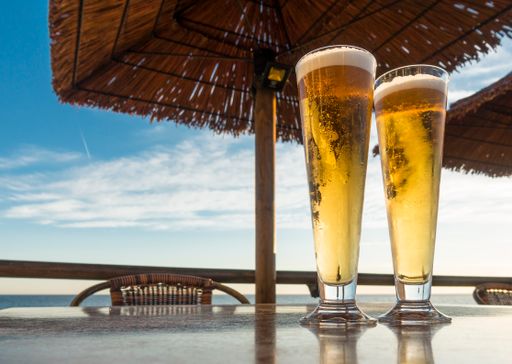 A closeup of two glasses of beer on a table in a beach restaurant on the backdrop of the sky