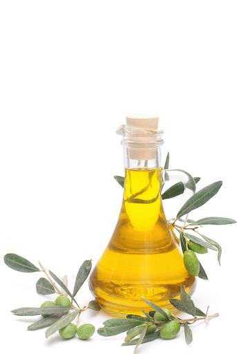 Carafe with olive oil and a fresh twig of olives with leaves, isolated on a white background