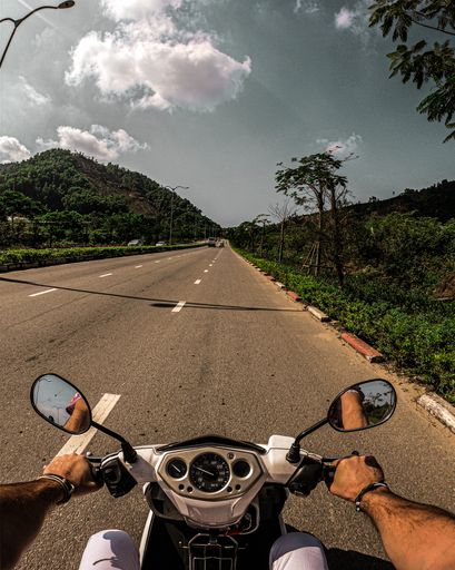 A vertical shot of a person riding a motorcycle on the road