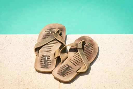A set of flip flops at the border of a swimming pool