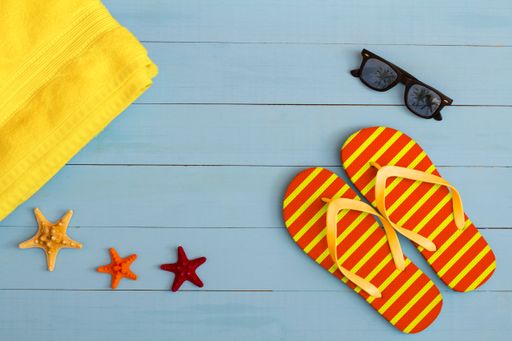 A cool view on painted light blue wood table with sunglasses, flip flops, towel, and starfish