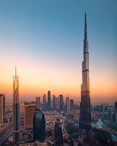 Aerial view of Burj Khalifa and Dubai skyline at sunset, showcasing modern skyscrapers and vibrant cityscape.