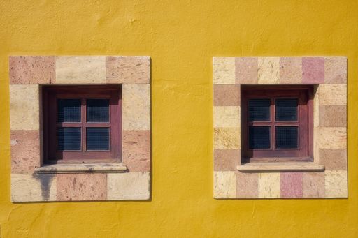 A closeup shot of square windows of a yellow building