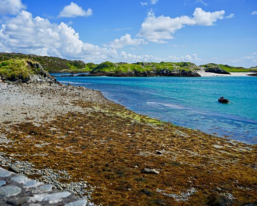 A shot of a picturesque seascape and mossy shore view with the background of green hills
