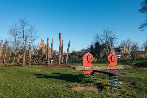 A beautiful shot of the playground in the park with the trees in the background
