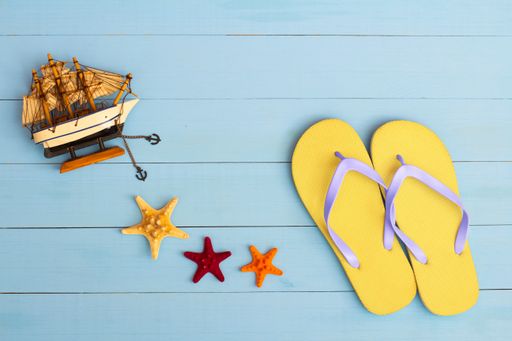 A cool view on painted light blue wood table with flip flops, sailboat, and starfish