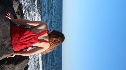 A shot of a female sitting on a rock and enjoying the beautiful seascape view
