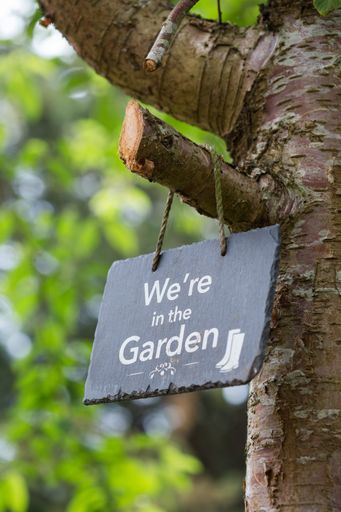 A sign of being in the garden hanging from a tree