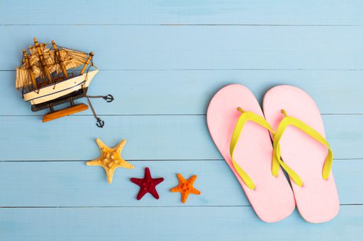 A cool view on painted light blue wood table with flip flops, sailboat, and starfish