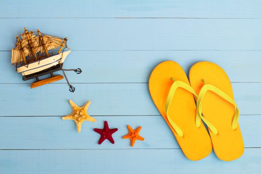 A cool view on painted light blue wood table with flip flops, sailboat, and starfish