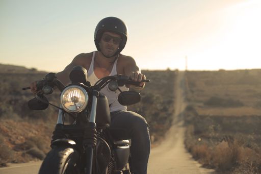 An adult Hungarian biker wearing a helmet and driving in the countryside
