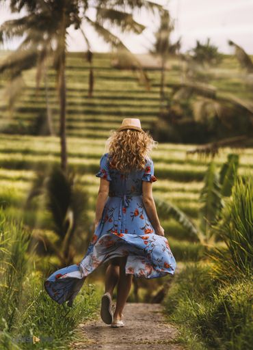 A vertical shot of a girl wearing a blue dress and walking along the path, taken from back