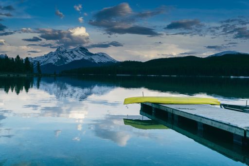 The mesmerizing view of the pier near the lake surrounded by lush nature and the mountains