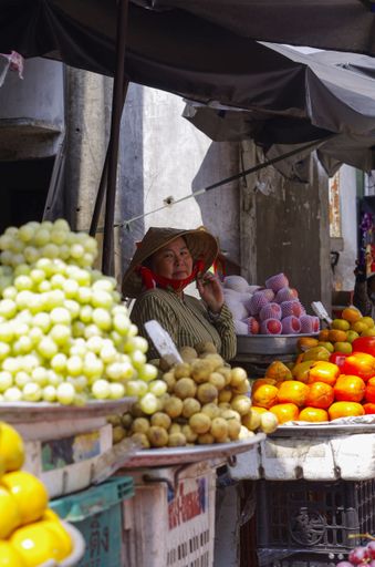 In a marketplace in vietnam, a local woman waits for business. She sells colourful fruit in the city streets