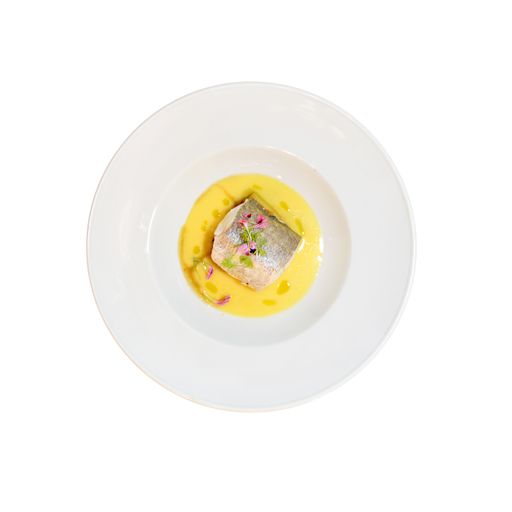 A fish in a yellow sauce in the plate on the white background