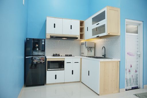 A minimalist kitchen interior with white wooden furniture and light blue walls