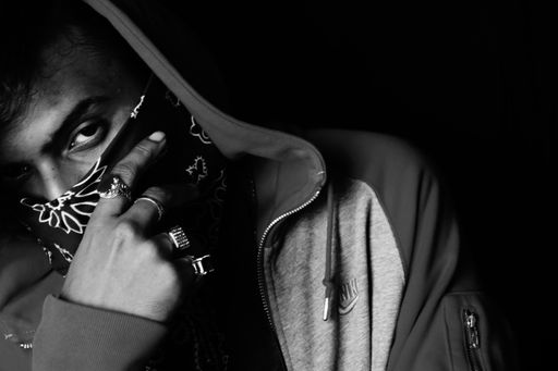 A grayscale shot of an Asian person wearing a hoodie and bandana
