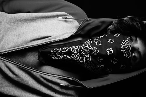 A grayscale shot of an Asian person wearing a hoodie and bandana