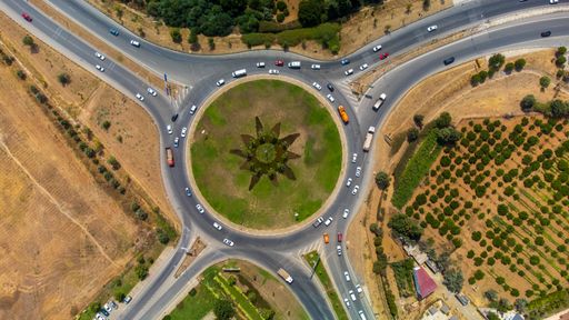 An aerial view of the cars driving on the roundabout road in the countrys