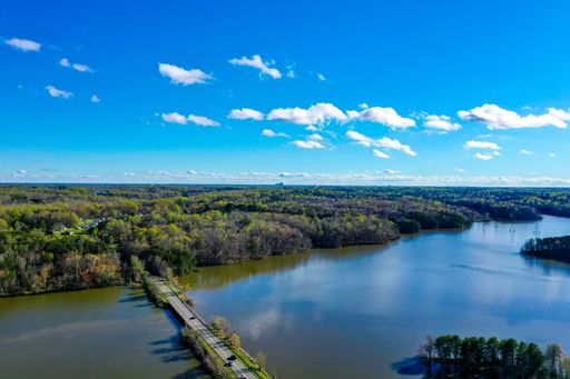 An aerial shot of a road near a lake in Greensboro under a blue sky