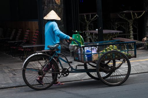 A guy with a hat riding his bike full of products in Ho Chi Minh City, Vietnam