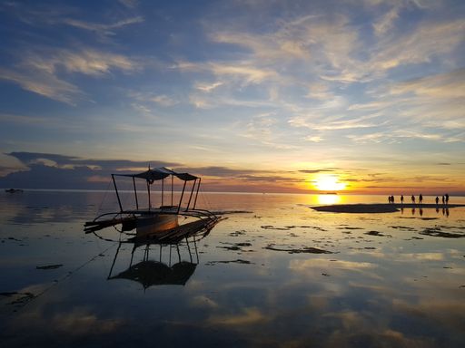 The silhouette of a fishing boat under a simple wooden shelter on the sea during a beautiful sunrise