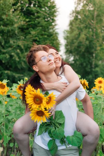 A vertical shot of a happy couple together in a sunflower field