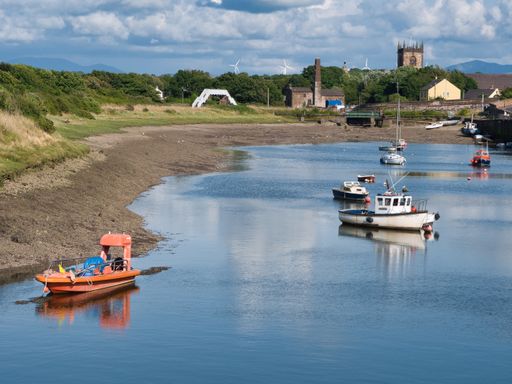 Small work boats moored in Workington harbour in Cumbria with the Lake District fells in the distance