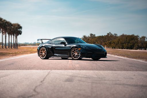 A sleek 2021 black Porsche GT4 on an asphalt road