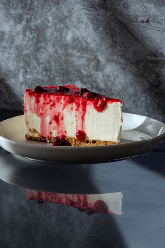 A vertical shot of delicious and rich cheesecake with cherry topping