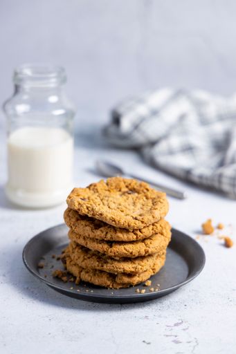 A vertical shot of delicious oatmeal cookies and a glass of milk on a surface