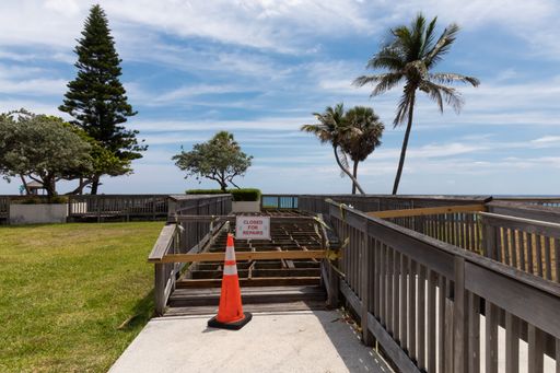 A walkway and decking by the Atlantic Ocean at Deerfield Beach Florida under construction with a warning sign and orange cone.