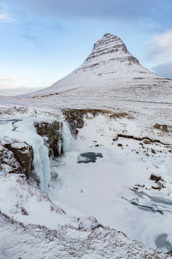 A vertical shot of the Kirkjufellfoss and Mountain in Grundarfjorour, Iceland