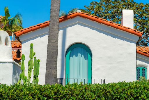 A closeup shot of a white house wall with a window and an orange roof