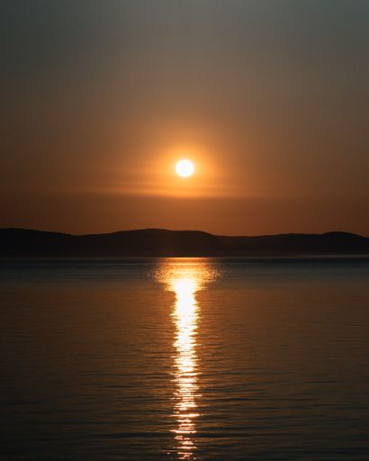 A vertical shot of a beautiful sunset sky reflecting on a calm sea