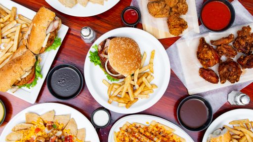 A top shot of a table with burgers, fries, chicken wings, salads, and sandwiches