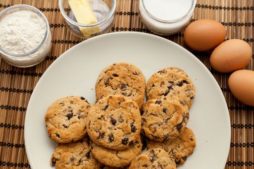 A closeup of a plate with chocolate chip cookies with ingredients.
