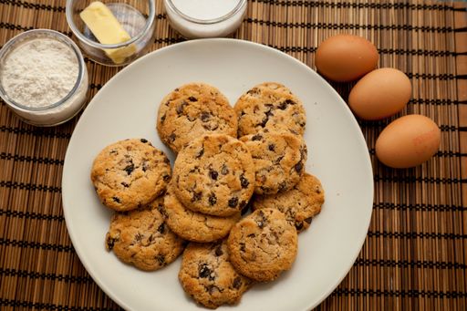 A closeup of a plate with chocolate chip cookies with ingredients.