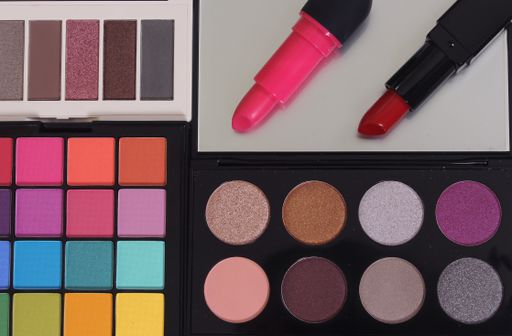 A top view of brightly colored cosmetic pigment palettes with two lipsticks