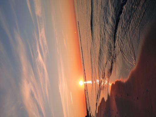 A vertical shot of a beach surrounded by the sea during a beautiful sunrise