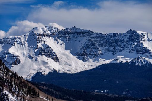 Snow-covered mountain peaks under a blue sky, showcasing a stunning winter landscape.
